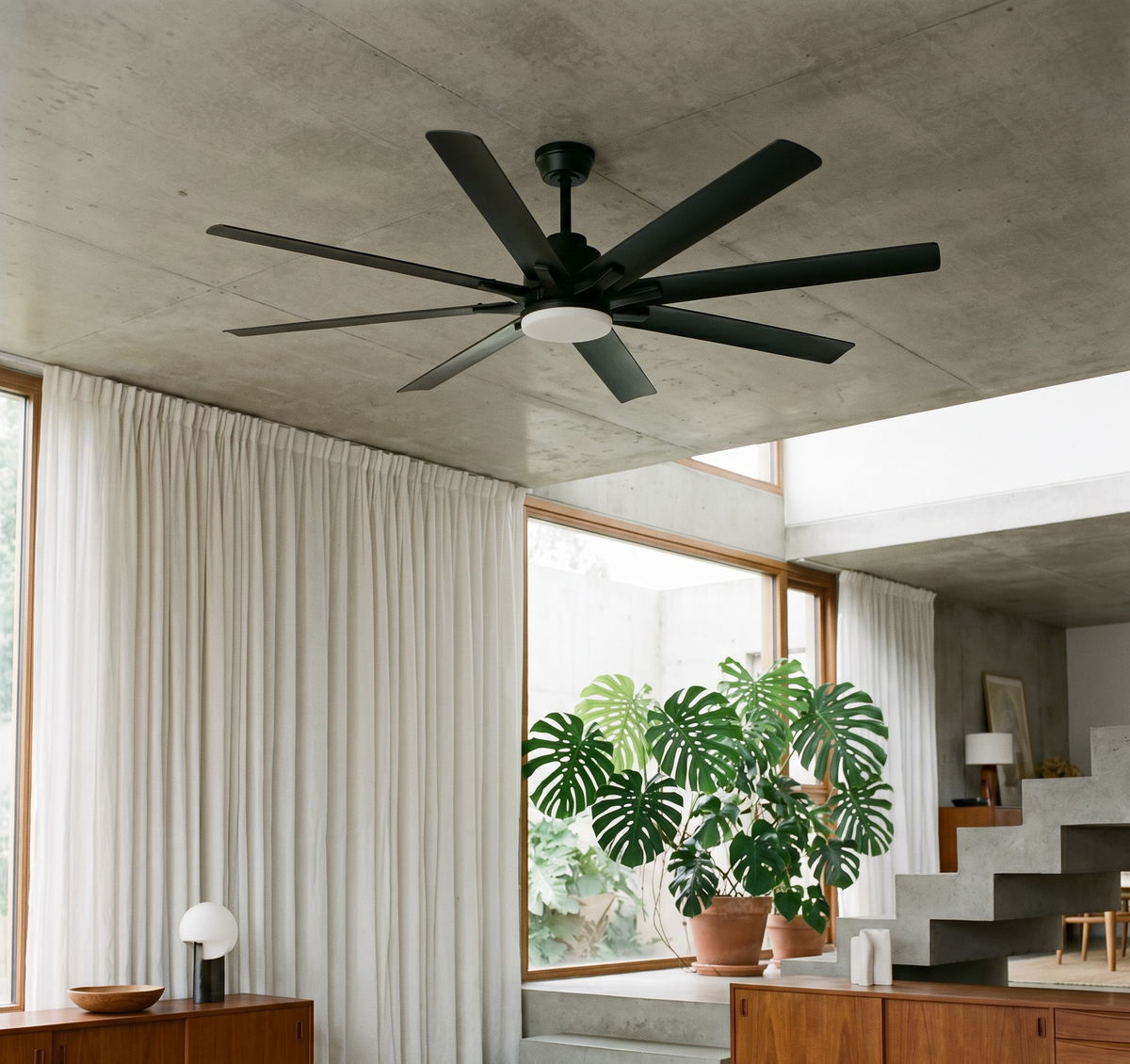 Ventilateur de plafond Ariaze XXL 8 pales noires installé dans un loft industriel, brassage d'air puissant pour grandes pièces